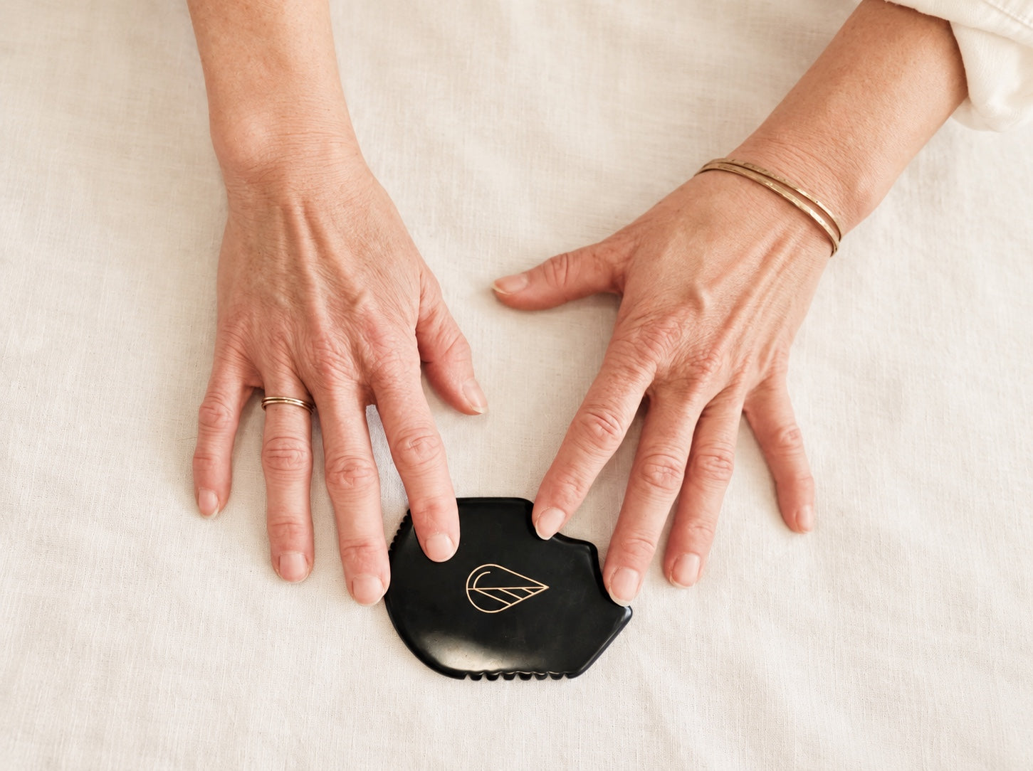Hands beside a black gua sha tool used in Spruce facial rituals